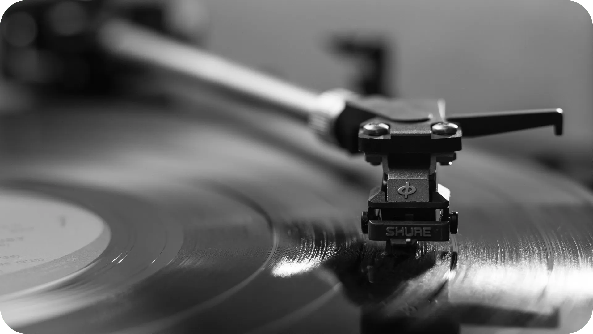 Black and white photo of a close up on the needle on a record player, while playing a record.